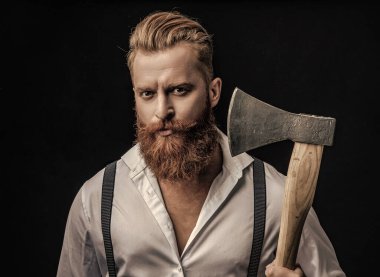 Siyaha izole edilmiş baltalı askılı vahşi bir adam. Saçları kızıl saçlı, olgun bir adam. Acımasız erkek modası. Erkek vahşeti. Eski moda pantolon askısı takan eski tip gaddar adam..