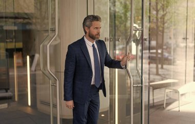 Takım elbiseli İspanyol işadamı ofis binasını terk ediyor. Patron ofisten ayrılıyor. İş adamı. Başarılı bir iş adamı ofise giriyor. Ofis kapısında yetişkin bir girişimci. Hizmet işi.