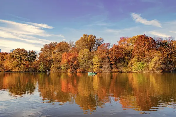 Sonbahar göletine park teknesi, New York. Manzaralı düşüş. Sonbaharda Central Park 'ta. Sonbahar manzarası. Göletteki tekne. Sonbahar doğa manzarası. Central Park 'ta sonbahar doğası. Mevsimlik sonbahar manzarası. Tekne sezonu.