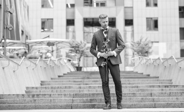 Smokinli zarif bir damat. Damat dışarıda smokin papyon giyer. Kırmızı güllü yakışıklı damat..