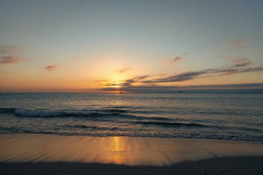 Yaz kumsalında deniz suyuyla sakin bir gün batımı.