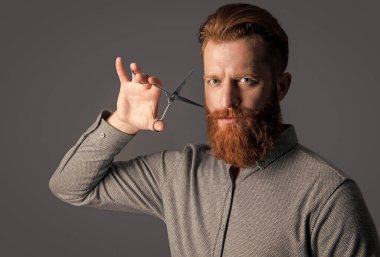 Adam berber kuaförlüğü gri arka planda izole edilmiş. Berber makasıyla kuaförlük yapan adam. Kuaför stüdyosunda berber. Berber adam kuaförlük için makas tutuyor. kuaförlük konsepti.