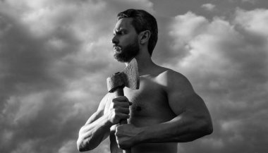 Baltalı üstsüz adam. Kafkasyalı adam baltayı tutuyor. vahşi adam gökyüzünde arka planda.