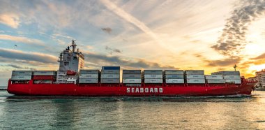 Miami, Florida, ABD - 3 Ocak 2025: Gündoğumunda konteyner gemisi. Kargo gemisi Seaboard Genesis ve konteynır Miami 'de. Yük konteynırı kargo gemisine yüklendi. Hava görüntülü kargo gemisi limana giriyor..