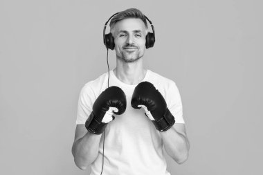 Spor salonunda spor adam boks yapıyor ve kulaklıkla müzik dinliyor mavi üzerine izole edilmiş spor salonunda..