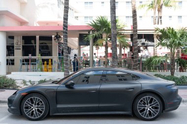 Miami, Florida, ABD - 20 Aralık 2024: Porsche Taycan 2023 elektrikli sedan. Elektrikli sedan araba Porsche Taycan. Siyah Porsche Taycan dışarıda park halinde. Porsche Taycan elektrikli sedan araba, yan görüş.