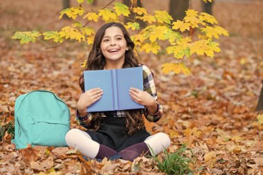 Okul eğitimi. Dışarıda kitap okuyan liseli kız. Genç kız sonbahar parkında kitap okuyor. Eğitim ve bilgi. Bilgi toplama günü. Kendi kendine eğitim. Sonbahar kitabı. Okula dönelim. Mutlu çocukluk.