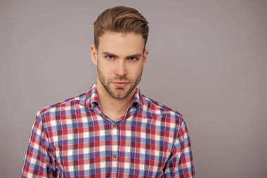 Tıraşsız adamın şık bir portresi. Gri yolda izole edilmiş bir adam. Kareli gömlek giyen milenyum adamı. Milenyum erkeğinin gündelik tarzı. Sıradan bir tişörtle genç bir adamın portresi. Boşluğu kopyala.