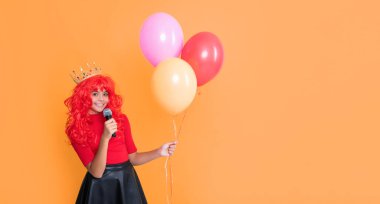 Sarı arka planda mikrofonlu ve parti balonlu pozitif çocuk..