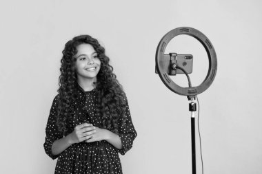 Uzun kıvırcık saçlı mutlu çocuk blog için video yapıyor.