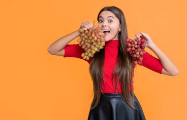 Şaşırtıcı kız sarı arka planda bir demet üzüm tutuyor..