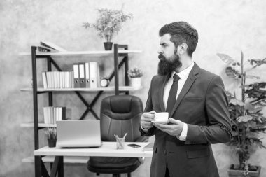 Ciddi sakallı iş adamı ofiste fotokopi alanı ve iş yeri olan kahve içiyor..