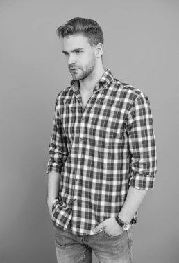 Sıradan gömlekli bir adamın portresi. Gri üzerinde kollarını çapraz tutuyor. Tıraşsız erkek derisi. Erkek güzelliği ve saç stili. Gündelik giyinen milenyum adamı. Yakışıklı genç adam. Yakışıklı adam..