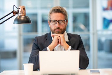 Çevrimiçi çalışan serbest çalışan. Ofiste dizüstü bilgisayar kullanan ciddi bir adam. Serbest iş yapma. Erkek ofis yöneticisi. İş adamının internet işi var. İş adamı başarısı. Serbest çalışan adam internette çalışıyor..