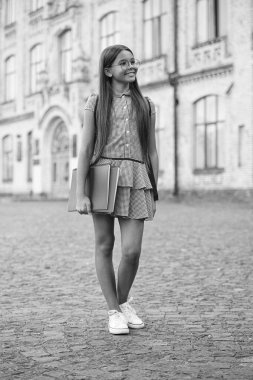 Okul çantası takan ve egzersiz kitabı tutan öğrenci kız. İlkokulun dışındaki mutlu genç kızın portresi. Gözlüklü kız öğrenci. Okula dönelim. Eğitim ve bilgi.