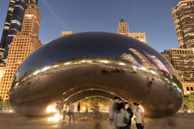 Chicago, Illinois, ABD - 22 Ekim 2024: Millennium Park ve ünlü Cloud Gate heykeli. Fasulye heykeli. Gökdelenli gece şehri manzarası. Chicago Milenyum Şehir Parkı. Bulut Kapısı.