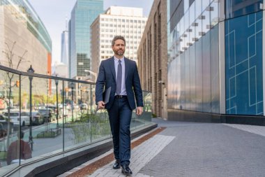 Takım elbiseli zengin adam. Dışarıda başarılı bir iş adamı. İşadamı şehirdeki iş toplantısına yürüyerek gitti. İş adamının iş başarısı. Takım elbiseli bir iş adamı. Üst düzey yönetici yürüyor. Şehir merkezinde..