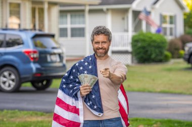 İspanyol adam ve Amerikan bayrağı. Amerika 'da vergi ödemek. Katma değer vergisi. Vergi sistemi. Vatansever adam işaret ediyor. Amerikan bayrağı ve dolar parası olan adam. Enflasyon konsepti. Amerikan vergi politikası.