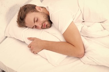 Geceleri uyuyan bir adam. Uykulu adam beyaz yatak odasında uyuyor. Uyuyan genç adam uyuyor. Rahat bir yatakta huzur içinde dinleniyor. Kapalı gözlerle yalan söylemek. Derin erkek uykusu. Sabah uykusu.