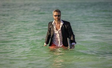 Yaz tatilindeki yakışıklı iş adamı. Denizdeki iş adamı dizüstü bilgisayarını tutuyor. Yaz işi. Yaz Denizi Sahili 'nde serbest yazar. İş adamı iş gününden sonra ferahlatıcı. iş tatili.