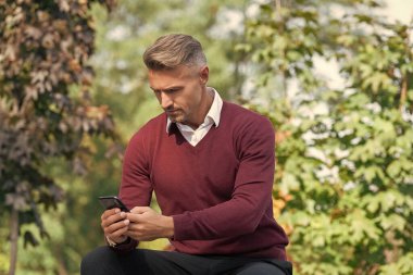 İnternet işi. İşadamı sonbaharda telefon kullanır. Sonbahar adamı telefonu kullanır. Sıradan bir iş adamı gibi. İş adamı dışarıda telefonla mesajlaşıyor. İş iletişimi tarzı. Çevik iş.