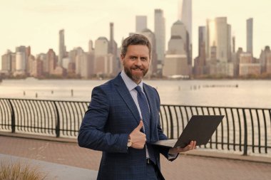 New York 'ta serbest çalışan bir iş adamı. İnternette çalışan bir iş adamı. İş adamı dışarıda bilgisayar ya da dizüstü bilgisayarda çalışmakla meşgul. Adam internet tarayıcısından iş e-postası ve sörf yolluyor. Başparmak yukarı..