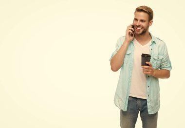 Telefonla ve kahveyle arayan adam. Konuşuyorduk. Kahve molası. Sabah araması. Genç meşgul bir adam telefonda konuşuyor. Millennial 'daki adam telefonla arıyor. Beyazdan izole edilmiş. Boşluğu kopyala.