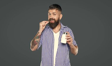 Olgun bir adam gri arka planda vitamin hapı alıyor..