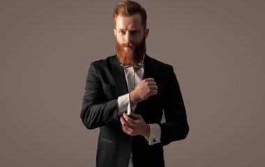 İrlandalı adam kelepçeleri ayarlıyor. Smokin giyen sakallı adam. Resmi kıyafet giymiş sakallı bir iş adamı. Yakışıklı kızıl saçlı beyefendi stüdyosu Grey 'de izole edilmiş..