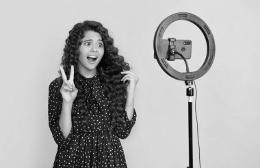 Uzun kıvırcık saçlı kafası karışık bir çocuk blog için video yapıyor.