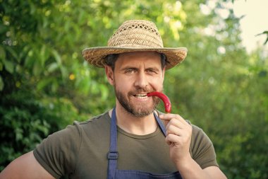 man greengrocer in straw hat with chili pepper vegetable.