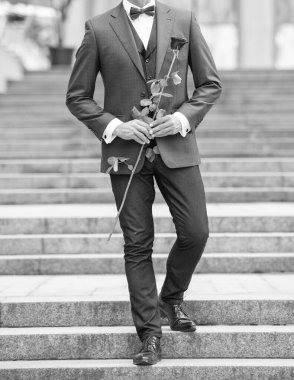 Smokinli damat kılıklı adam manzarası. Damat dışarıda smokin papyon takıyor. Kırmızı güllü damat.