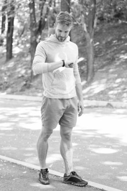 Fitness aleti olan bir koşucu. Fitness için akıllı seğirme. Spor ekipmanlı, formda bir adam. Akıllı saat kontrolü zamanı. İzleme sporu spor kıyafetleriyle sonuçlanır. Mobil uygulama kullan.