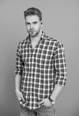 Kablosuz kulaklıklı bir adam. Adam gri renkte izole edilmiş kulaklık kullanıyor. Modern kablosuz kulaklıklar. Elsiz kulaklık. Kulaklık cihazı aksesuarı. Kablosuz kulaklık cihazı. Kulaklık aksesuarları. Aletli adam..