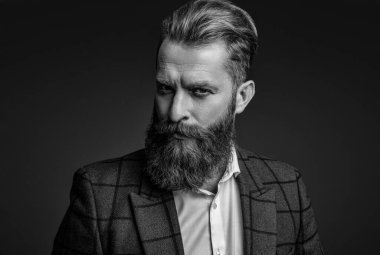 Gri yolda yabani sakallı adam. Zarif takım elbiseli hırslı bir adam. Erkekler için resmi moda. Erkek giyim modeli. Takım elbiseli şık bir adam. Sakallı bir iş adamı. İmza biçimi.