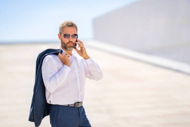 İş adamının telefon görüşmesi var. Reklamlar. Telefon kullanan bir iş adamı. İş görüşmesi. Meşgul iş adamı telefonda konuşuyor. Ofis çalışanı dışarıda telefonla konuşuyor. Akıllı telefondan iş adamı konuşması.