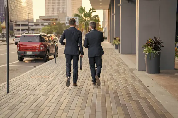 New York 'ta iş arkadaşı yürüyüşü. Başarı. Takım elbiseli işadamları dışarıda yürüyor. Şehirde yürüyen ve konuşan iki işadamı. İş adamları konuşuyor. Yürüyen ve konuşan iki iş adamı. Arka plan.
