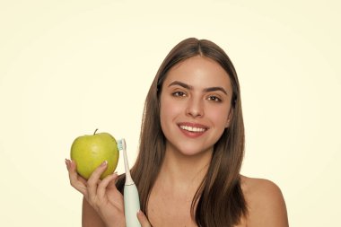 Dişlerini fırçalayan bir kız. Beyaz dişler. Diş sağlığı kliniği. Elektrikli diş fırçası. Beyaz tenli dişlek kadın gülüşü. Dişlerini elektrikli diş fırçasıyla fırçalayan bir kadın. Akıllı diş fırçası.