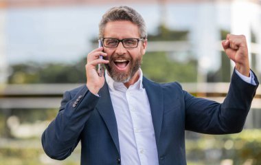 Telefonu olan heyecanlı bir İspanyol iş adamı. İş iletişimi. Müzakere çevrimiçi. İş adamı dışarıda telefonla konuşuyor. Telefon kullanan bir iş adamı. Takım elbiseli adam telefonu..