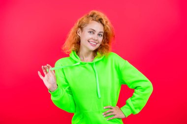 Çekici bir kadının şık bir görünüşü var. Kız havalı görünüyor. Minimum giysi. Pembe üzerine izole edilmiş kapüşonlu günlük kıyafetler giyen kızıl saçlı kadın. Yaşam tarzı konsepti. Kapüşonlu kadın model. Moda yeteneği..