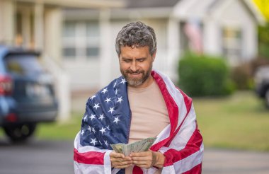 Amerika 'da vergi ödemek. Katma değer vergisi. Vergi sistemi. Vatansever adam para sayıyor. Amerikan bayrağı ve dolar parası olan adam. Enflasyon konsepti. Amerikan vergi politikası. İspanyol ve Amerikan bayrağı.