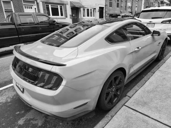 New York City, ABD - 10 Mart 2024: 2018 Ford Mustang sarı spor arabası, köşedeki manzara.