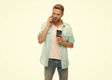 Genç adam telefonda konuşuyor. Millennial 'daki adam telefonla arıyor. Beyazdan izole edilmiş. Telefonla ve kahveyle arayan adam. Konuşuyorduk. Kahve molası. Sabah araması. Ciddi konuşma.