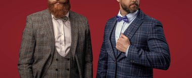 Smokinli adamlar kırmızıda izole edilmiş. Formalite icabı smokin giyen adamlar. Smokinli adamlar resmi kıyafet giyerler. Papyonlu, erkek giyimli şık erkekler. Kırpılmış manzaralı iki iş adamı.