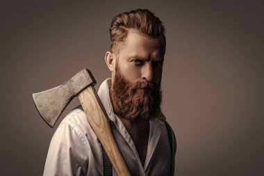 Sakallı adam gri yolda izole edilmiş. Sakallı adam, baltayı tut. Saç ve sakal bakımı. Yakışıklı, sakallı, vahşi adam. Sakal şekillendirme. Bıyıklı, Kafkas bir hippi. Erkeklik algısı.