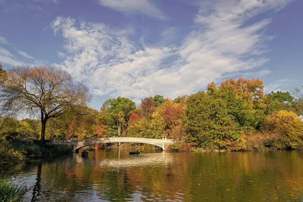 New York City, ABD - 25 Ekim 2023: Central Park 'ta kürek çeken insanlar. Sonbahar ağaçlı Central Park. Sonbahar doğası. Gölde teknesi olan Central Park. Sonbahar manzarası. Güneşli hava.