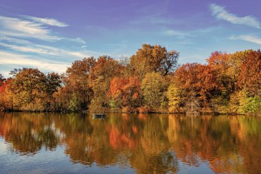 Sonbahar doğası. Central Park 'ta küçük bir gölde kayık. Sonbaharda Central Park Gölü 'nde insanların kürek çektiği bir yer. Central Park güneşli sonbahar gününde renk değiştiriyor. Sonbahar manzarası. Romantik kayık gezileri.