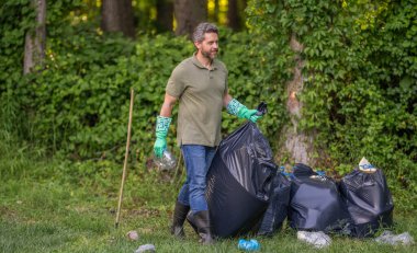 Çevresel koruma. Çevreci adam. Çevresel koruma. Çevreyi koru. Çevre plastik kirliliği. Gönüllü adam ormanda çöp topluyor. Boşluğu kopyala.
