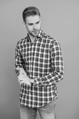 Gri yolda izole edilmiş bir adam. Kareli gömlek giyen milenyum adamı. Milenyum erkeğinin gündelik tarzı. Sıradan bir tişörtle genç bir adamın portresi. Tıraşsız adamın şık bir portresi. Damalı moda.