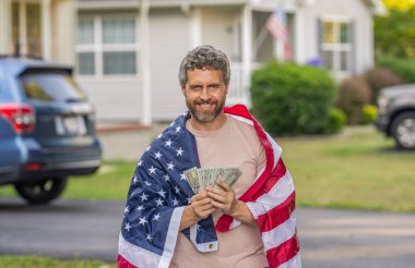 Amerika 'da vergi ödemek. Katma değer vergisi. Vergi sistemi. Vatansever adam. Amerikan bayrağı ve dolar parası olan adam. Enflasyon konsepti. Amerikan vergi politikası. İspanyol adam ve Amerikan bayrağı. ABD 'de maaş.